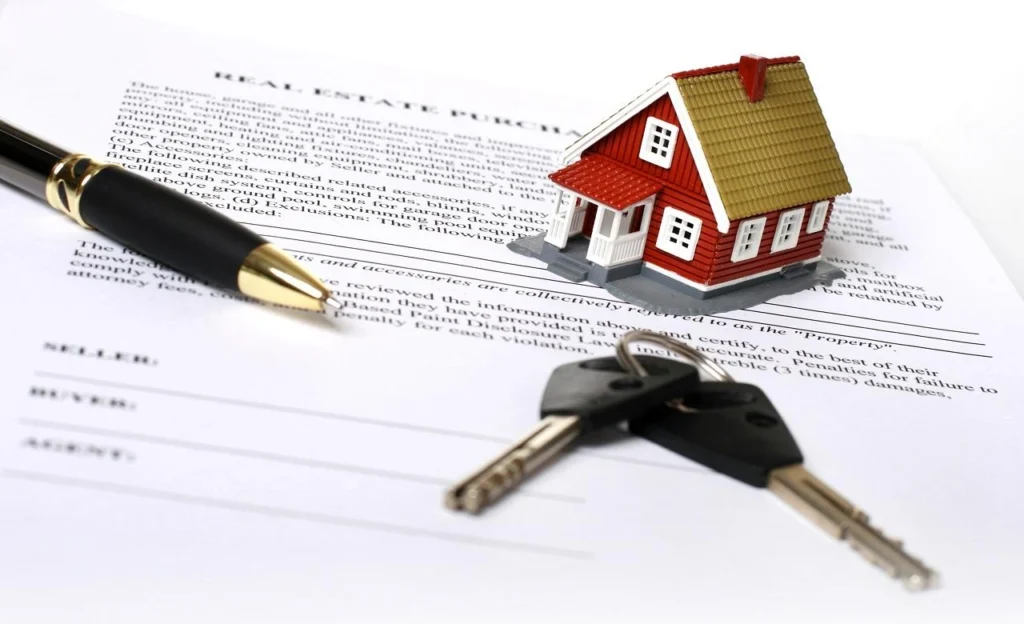 House model placed on real estate documents with a set of keys, symbolizing property ownership, home buying, and real estate investment.